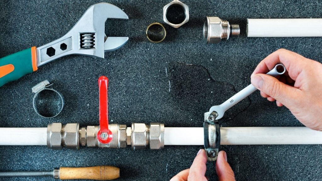 Plumber repairing a pipe valve with an adjustable wrench in Royal Palm Beach