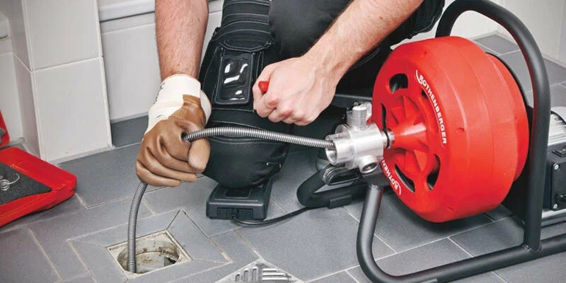 Plumber using a drain-cleaning machine in Royal Palm Beach