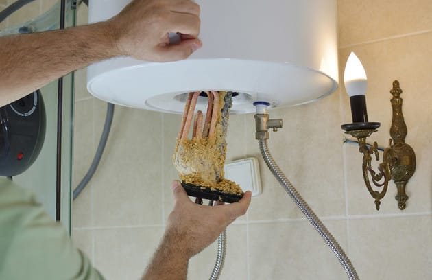 Technician removing mineral buildup from a water heater in Royal Palm Beach