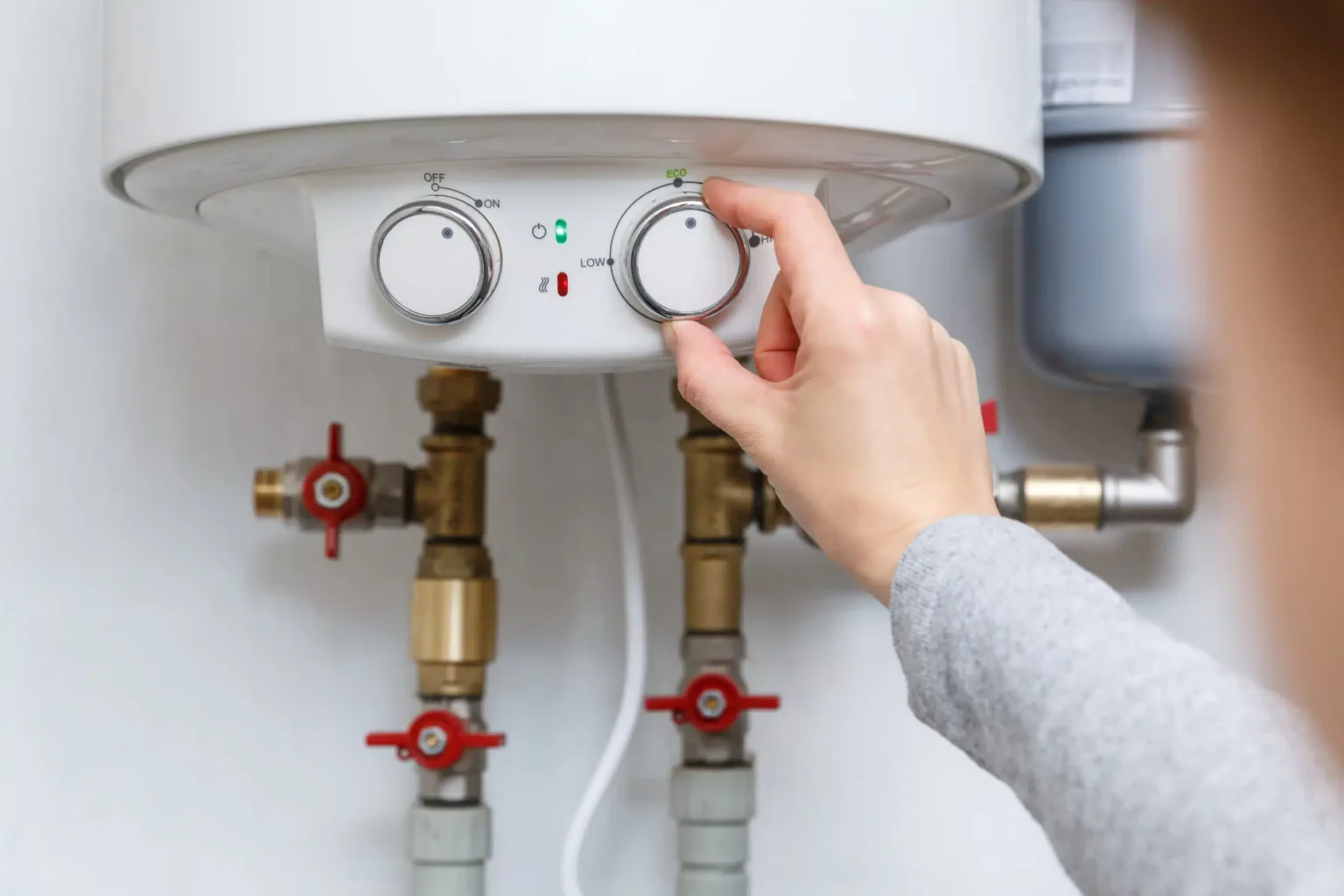 Homeowner adjusting the temperature controls on a water heater in Royal Palm Beach